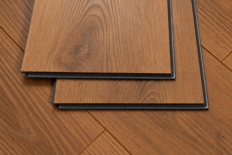 Close-up of laminate flooring planks with black HDF cores and wax-sealed edges